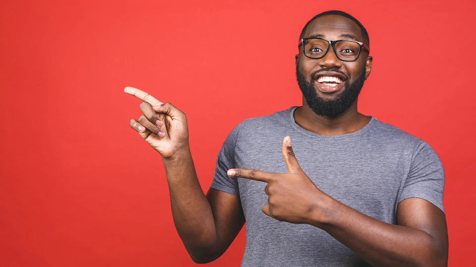 Homme souriant portant des lunettes sur un fond rouge